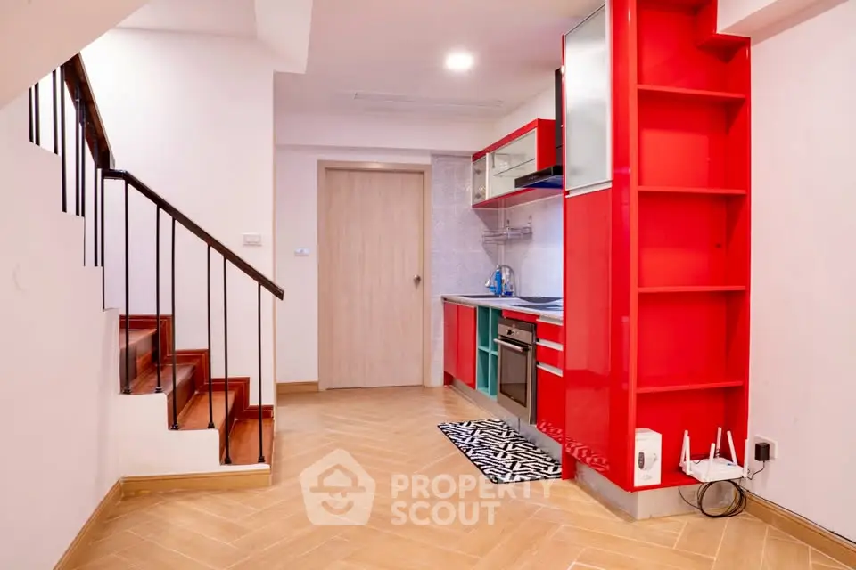 Modern kitchen with vibrant red cabinetry and sleek appliances in a stylish apartment.