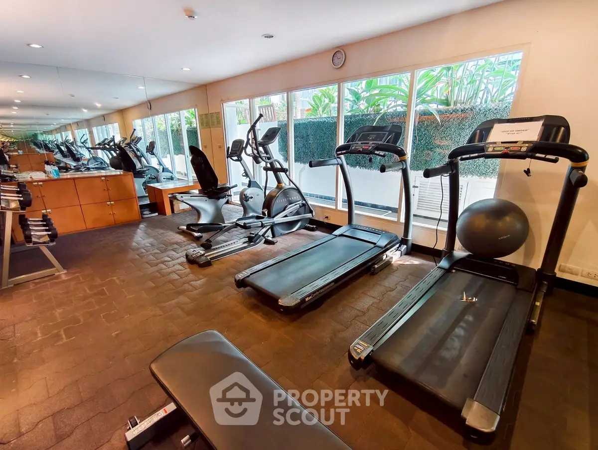Spacious gym with modern equipment and large windows for natural light