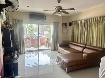 Spacious living room with leather sectional sofa and large windows for natural light.