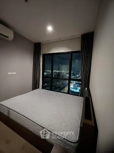 Cozy bedroom with city view, featuring a large window and modern decor.