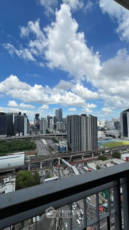 Stunning cityscape view from high-rise balcony with blue skies and urban skyline.