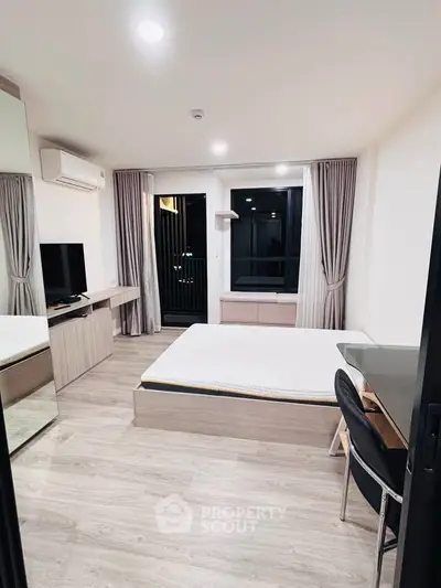 Modern bedroom with sleek furniture and large window offering natural light.