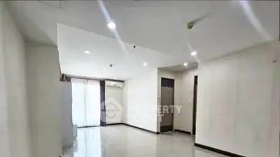 Spacious empty living room with modern lighting and large windows in a contemporary apartment.