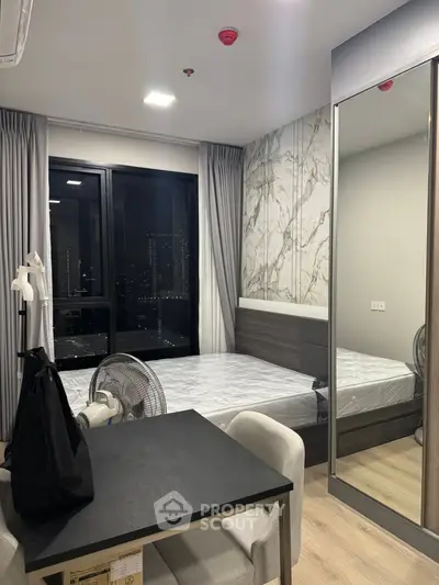 Modern bedroom with city view, stylish decor, and mirrored wardrobe.