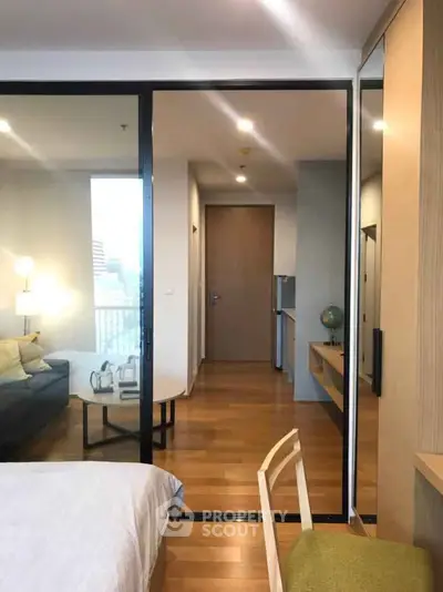 Modern apartment interior with wooden flooring and glass partition, featuring a cozy living area and stylish decor.