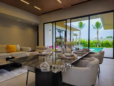 Luxurious open-plan living and dining area with pool view, elegant decor, and modern furnishings.