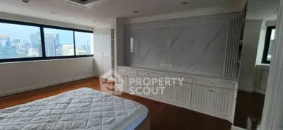 Spacious bedroom with city view and elegant built-in storage in modern apartment.