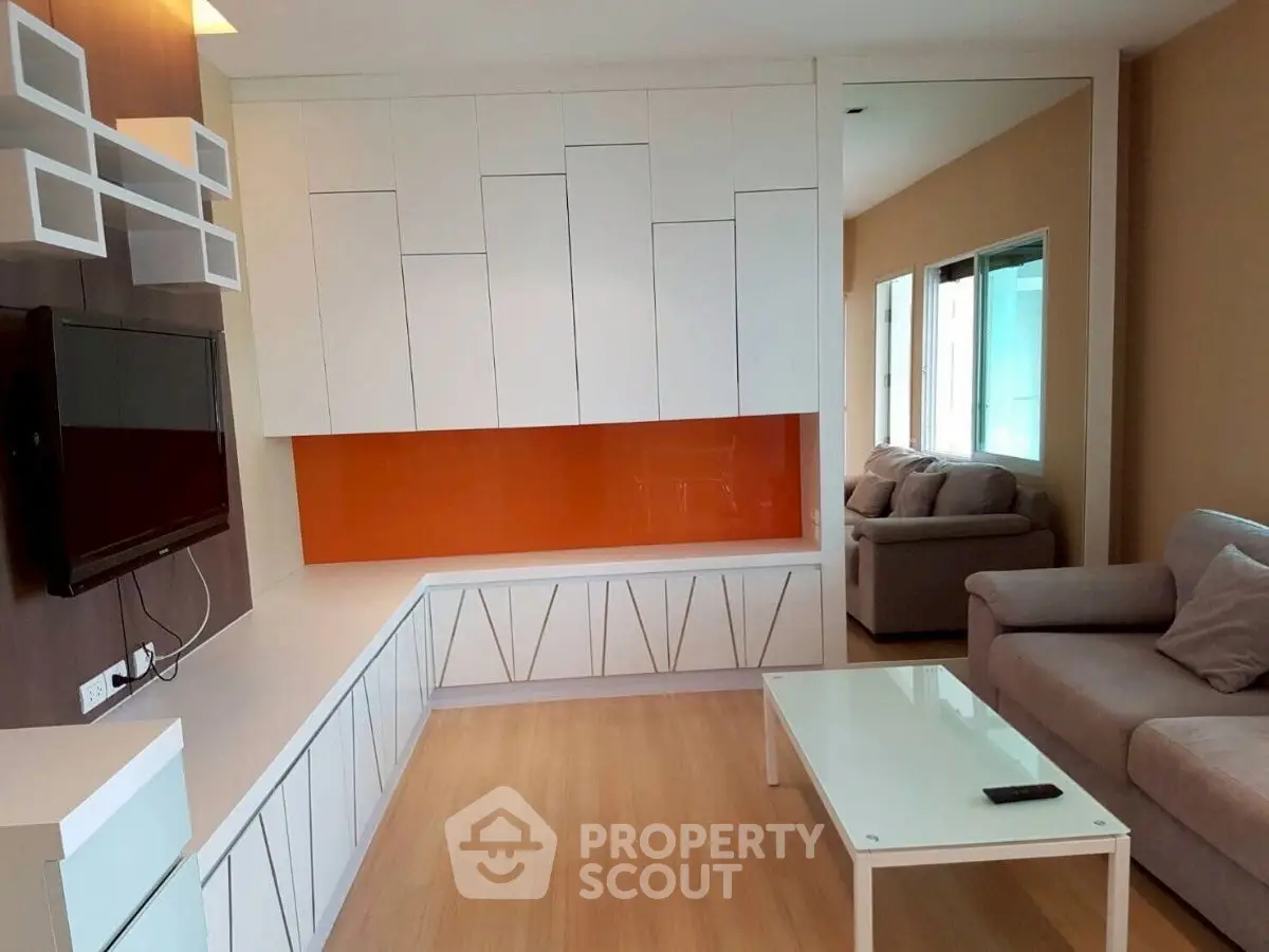 Modern living room with sleek white cabinetry and vibrant orange accent wall