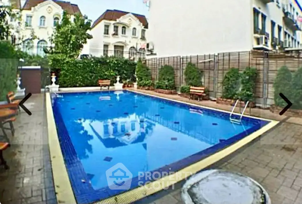 Charming residential pool area with elegant landscaping and seating, perfect for relaxation and leisure.