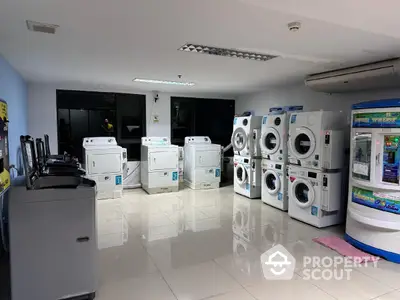 Modern laundry room with multiple washing machines and dryers in a sleek, tiled space.