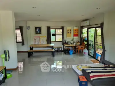 Spacious living room with modern decor and large windows offering garden views, perfect for family gatherings.
