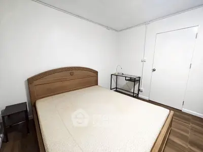 Cozy bedroom with wooden bed frame and minimalist decor, perfect for a peaceful retreat.