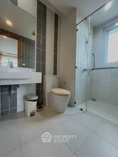 Modern bathroom with glass shower and sleek fixtures in a contemporary apartment.