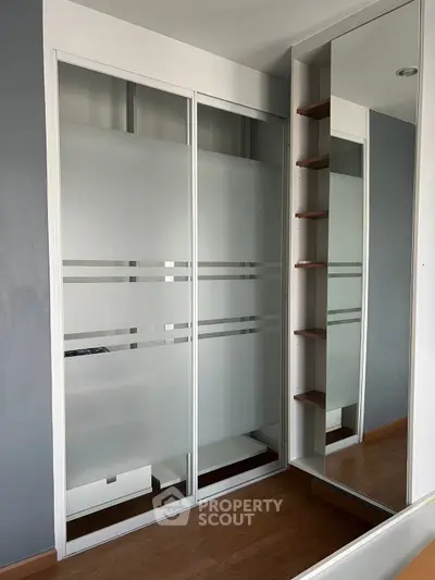 Modern bedroom with sleek sliding closet doors and mirrored storage unit.