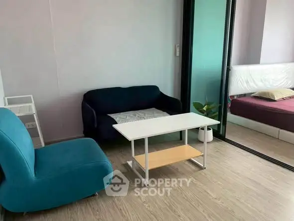 Modern living room with stylish furniture and sliding glass doors leading to a cozy bedroom.