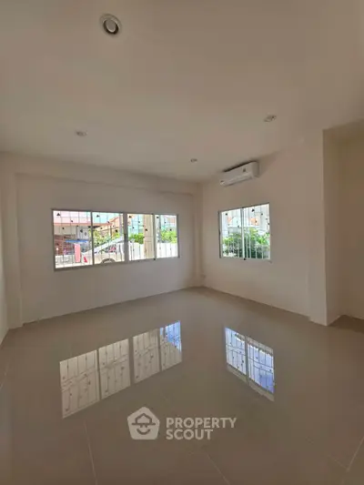 Spacious unfurnished room with large windows and air conditioning, perfect for customization.