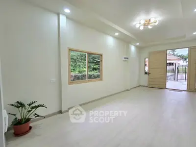 Spacious and bright living room with modern lighting and garden view, perfect for family gatherings.
