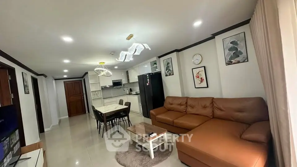 Modern living room with open kitchen, stylish decor, and cozy seating area.