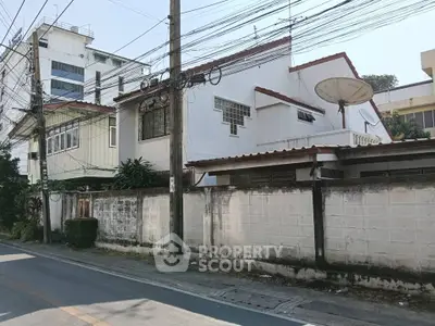 Charming residential house with satellite dish and secure perimeter wall in urban setting.