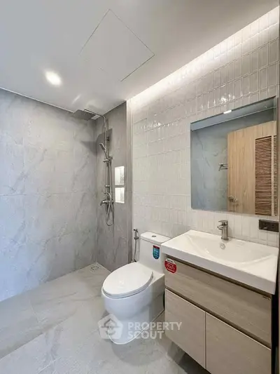 Modern bathroom with sleek fixtures and minimalist design, featuring a shower and vanity.
