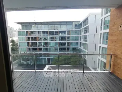 Modern apartment balcony with glass railing overlooking contemporary building