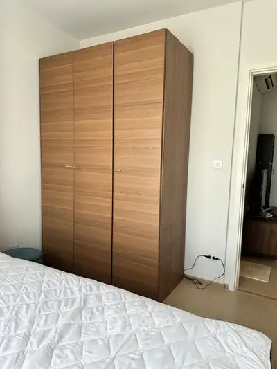 Modern bedroom with sleek wooden wardrobe and cozy bed setup.