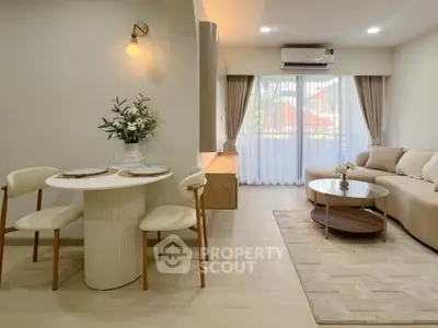 Elegant living room with modern decor, cozy seating, and natural light from large windows.