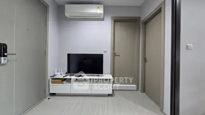 Modern living room with sleek TV setup and air conditioning in a minimalist apartment.