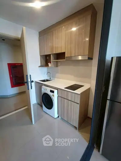 Modern compact kitchen with sleek cabinetry and integrated washing machine