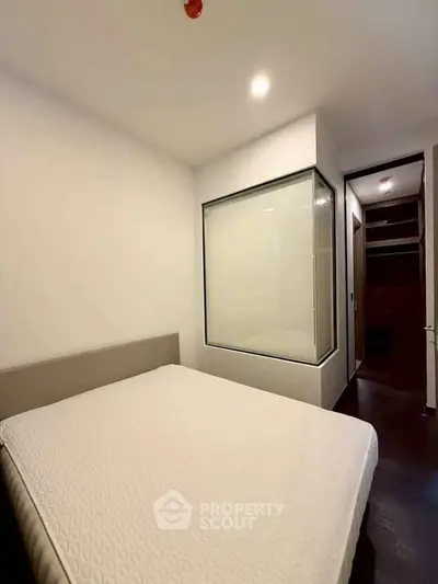 Modern bedroom with minimalist design and large window for natural light.