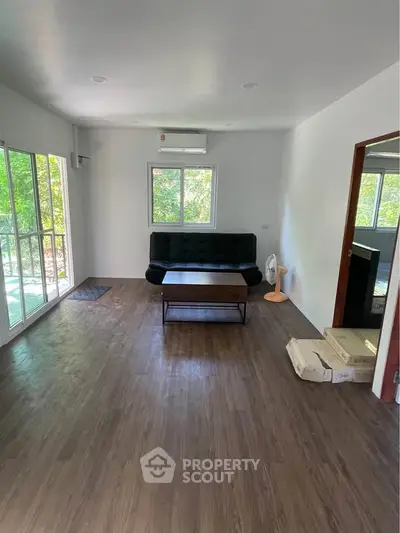 Spacious living room with modern sofa and large windows offering natural light.