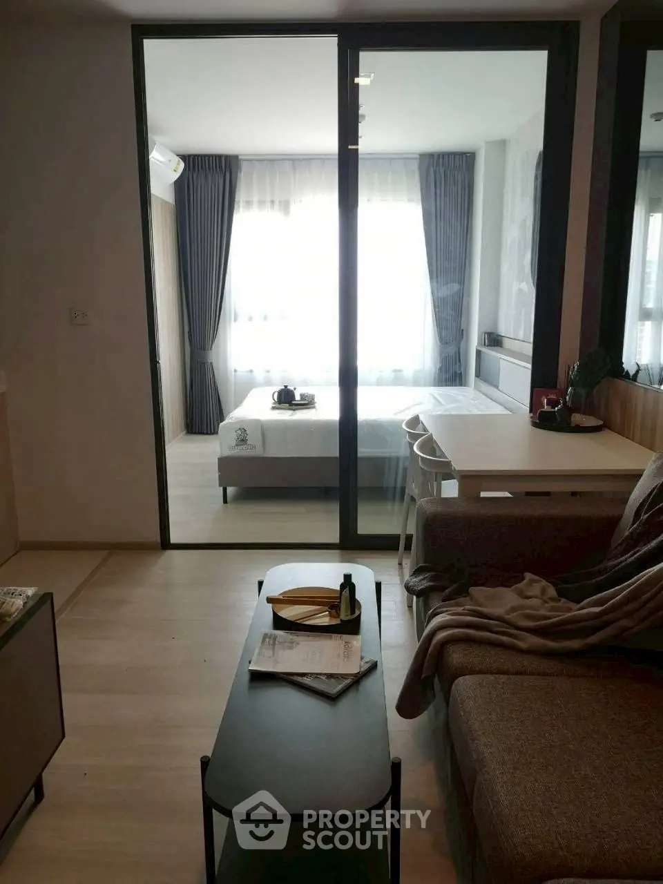 Modern studio apartment with cozy living area and bedroom separated by glass partition.