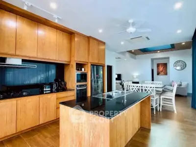 Spacious modern kitchen with wooden cabinetry and island, open layout to dining area, perfect for entertaining.