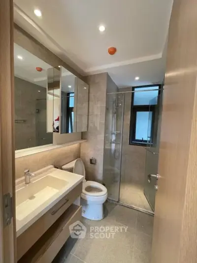 Modern bathroom with glass shower and sleek vanity in contemporary apartment.
