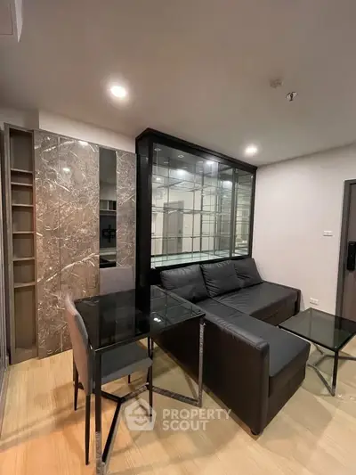 Modern living room with sleek black sofa and glass dining table in stylish apartment.