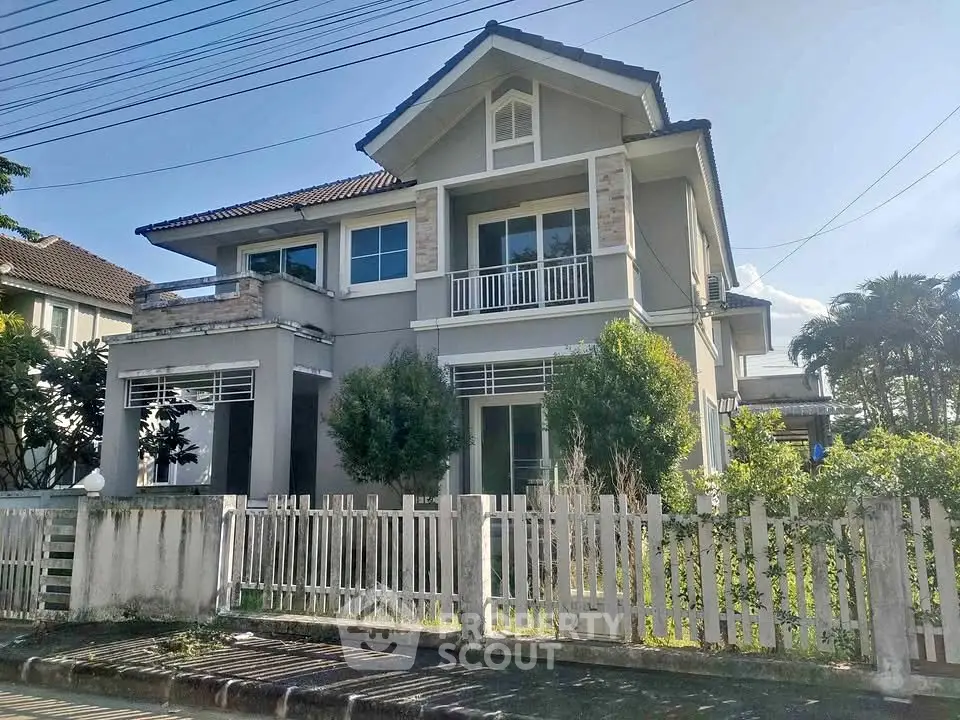 Charming two-story house with fenced yard and lush greenery in a serene neighborhood.