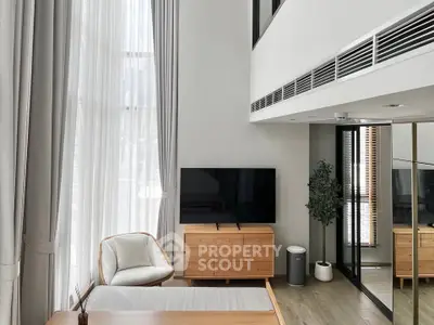 Modern living room with high ceilings, large windows, and stylish furniture in a luxury apartment.