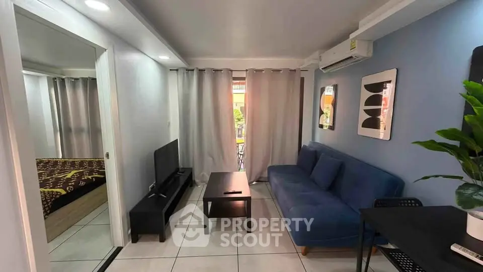 Modern living room with blue sofa, TV, and stylish decor in a cozy apartment setting.