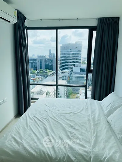Modern bedroom with stunning city view from large windows in high-rise apartment.
