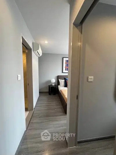 Modern apartment hallway leading to a cozy bedroom with stylish decor and natural lighting.
