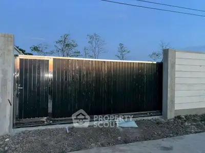 Modern black metal gate with concrete walls in a residential area