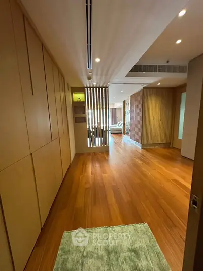 Spacious modern living area with wooden flooring and stylish partition, perfect for contemporary living.