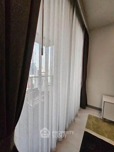 Spacious apartment with floor-to-ceiling windows and elegant curtains offering city views.
