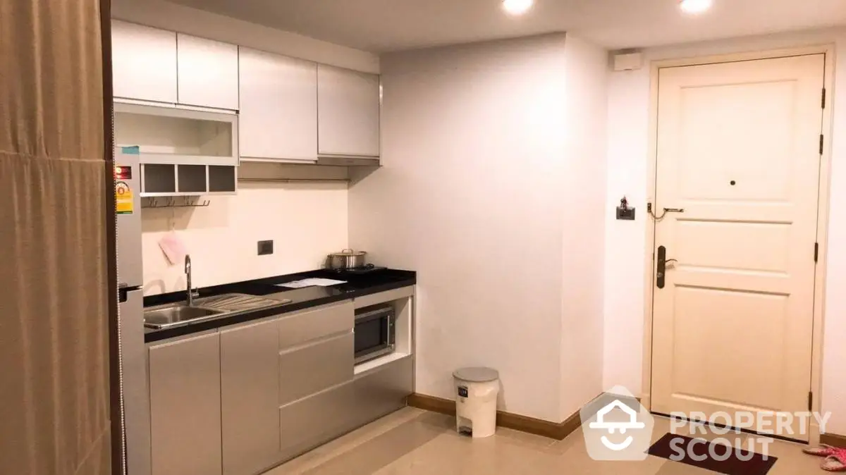 Modern compact kitchen with sleek cabinetry and integrated appliances in a cozy apartment.