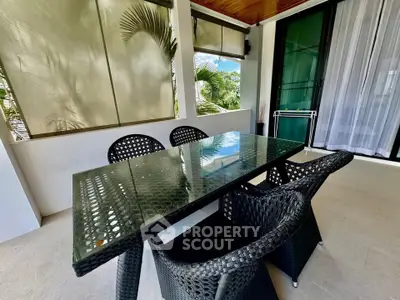Spacious balcony with modern glass table and wicker chairs, perfect for outdoor dining.