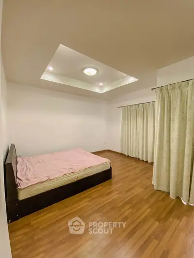 Spacious bedroom with wooden flooring and elegant ceiling design