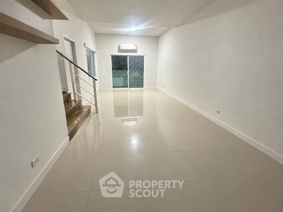 Spacious modern living room with sleek staircase and glossy tiled floors