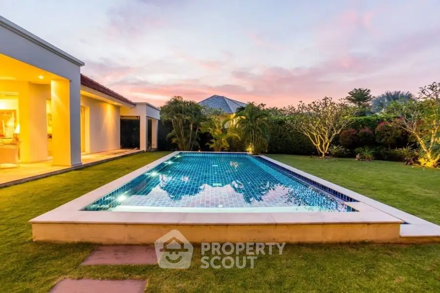 Luxurious backyard with a stunning pool and lush garden at sunset, perfect for relaxation and entertainment.