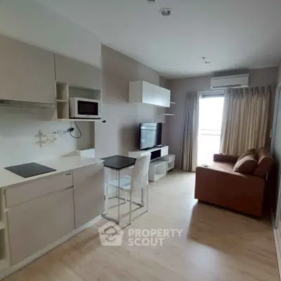 Modern living room with open kitchen, featuring sleek furniture and natural light.