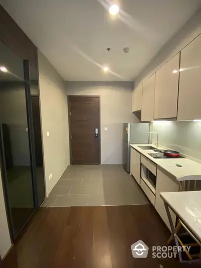 Modern kitchen with sleek cabinetry and built-in appliances, complemented by warm wooden flooring and ample lighting.